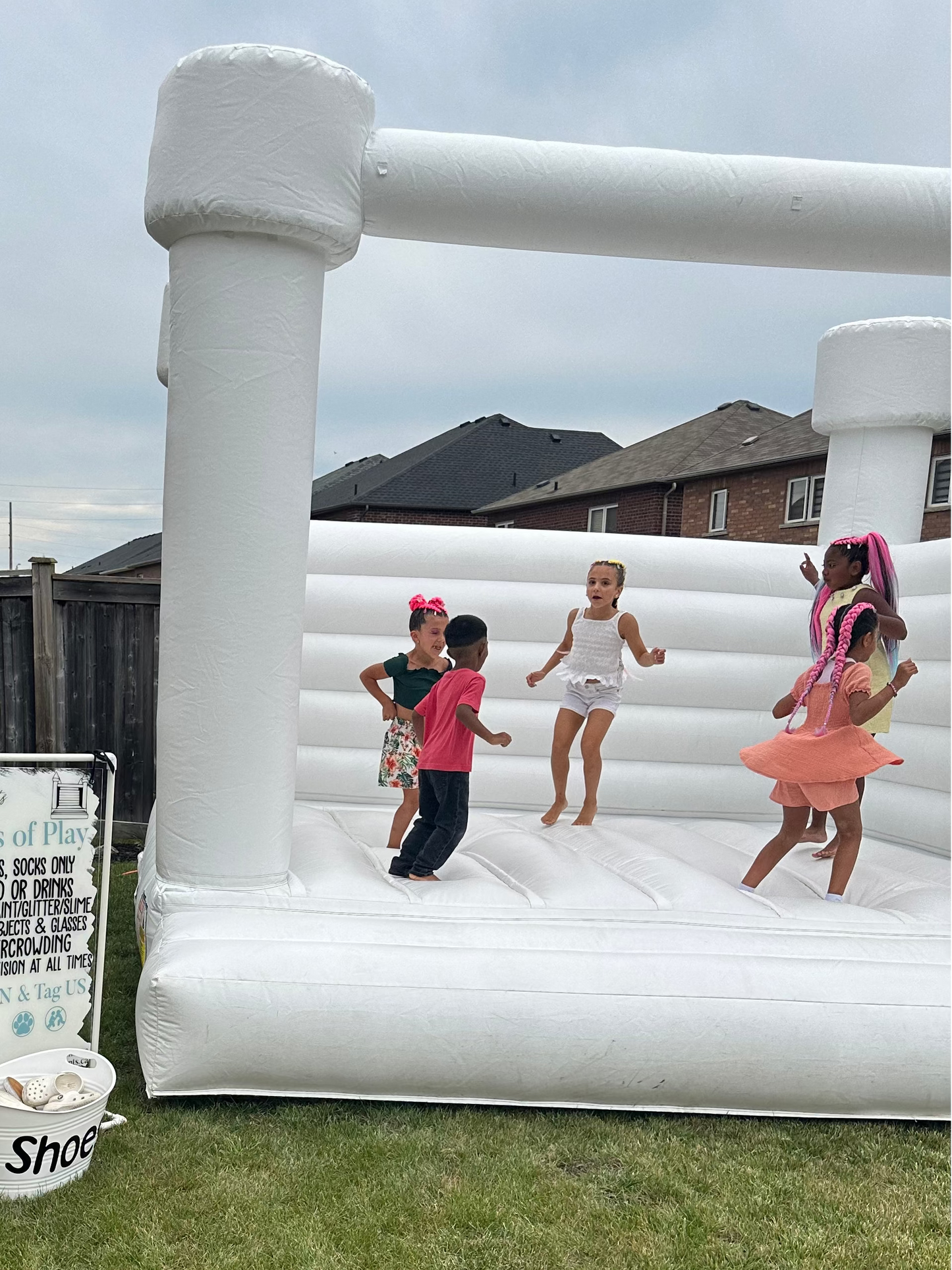 Children playing on an inflatable bounce house in a backyard.