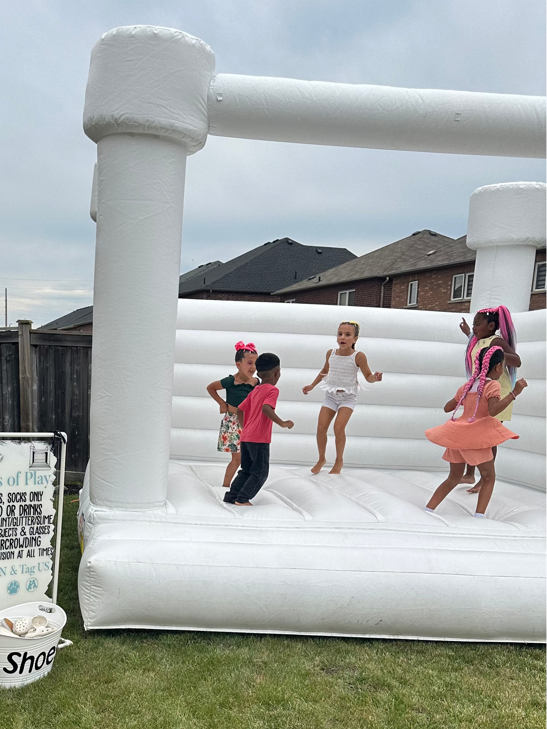 Children playing on an inflatable bounce house in a backyard.